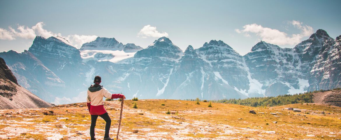 mann der oben auf berg steht und auf eine Bergkette blickt