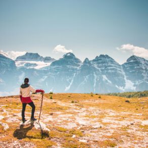 mann der oben auf berg steht und auf eine Bergkette blickt